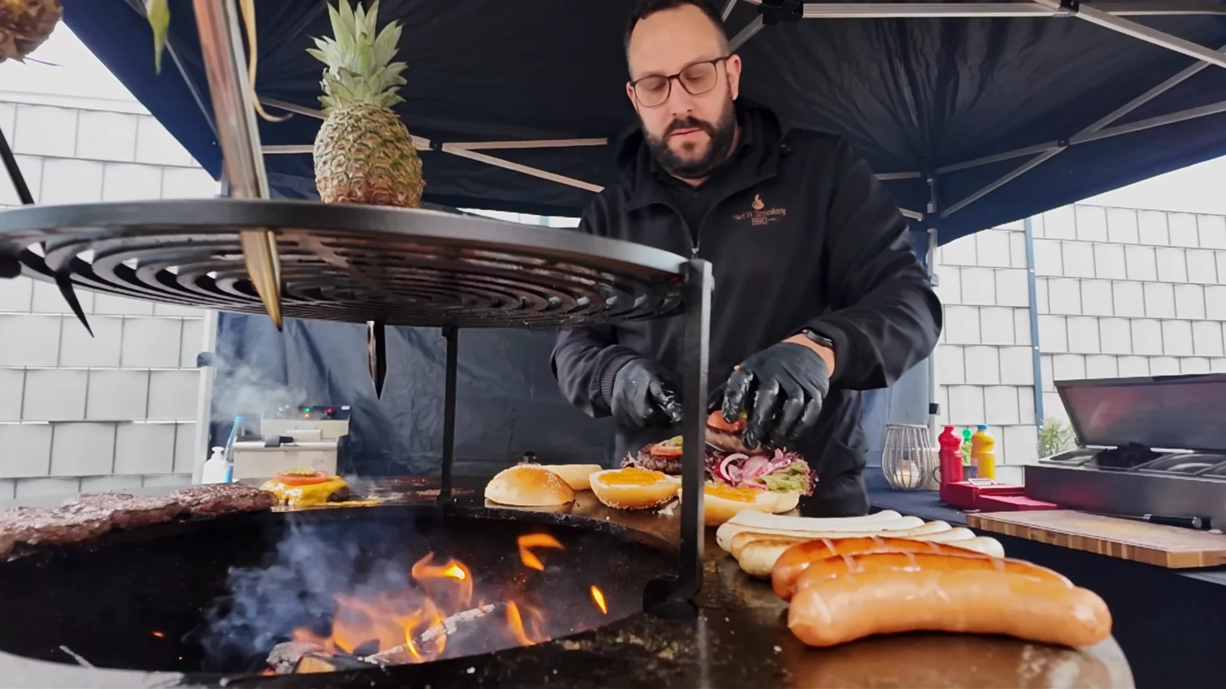Tobias Rohde baut an der Feuerplatte Burger, vorne Würstchen und Brötchen